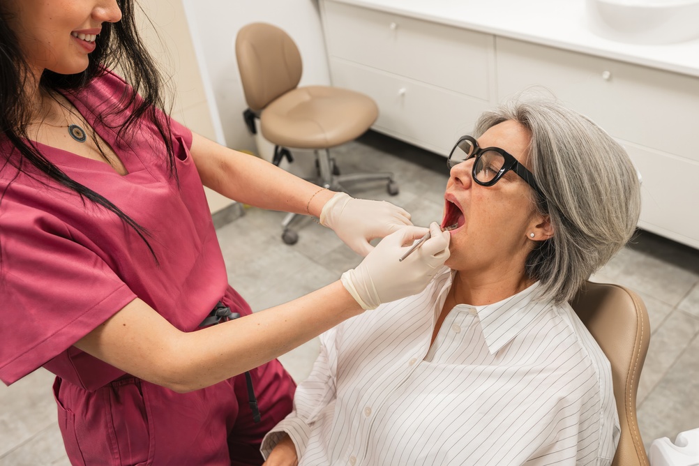 Photo of three smiling patients. The first patient is showing off their dental implants. The second patient is showing off their dental bridge. The third patient is showing off their dentures. No text on image.